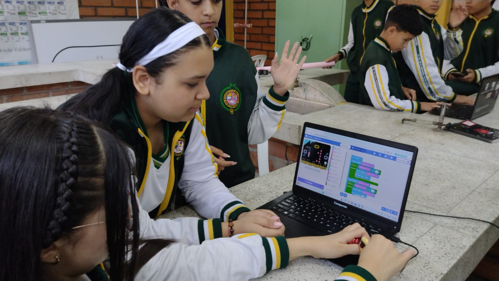 Estudiantes programando bloques micro:bit en laptop durante clase de ciencia