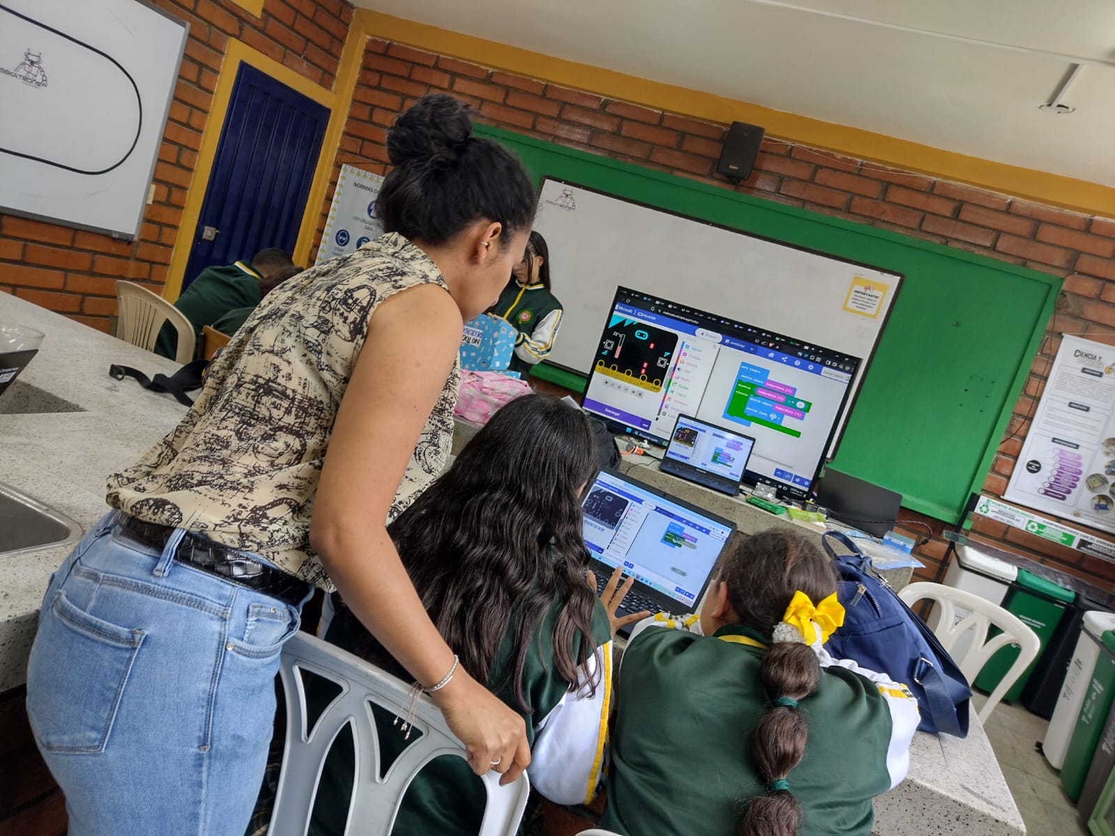 Docente orientando a alumnas en la creación de algoritmos en MakeCode